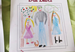 Obrazek z napisem dla Babci. Na obrazku narysowana jest dziewczynka w różowej sukience, obok mężczyzny w dżinsach oraznczarnej bluzie i kobiety w niebieskiej sukience. W ich nogach siedzi wiewiórka.
